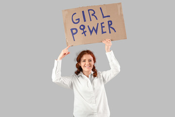 Beautiful young happy woman holding paper with text GIRL POWER on grey background. Women history...