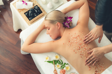 Obraz na płótnie Canvas Panorama top view woman customer having exfoliation treatment in luxury spa salon with warmth candle light ambient. Salt scrub beauty treatment in health spa body scrub. Quiescent