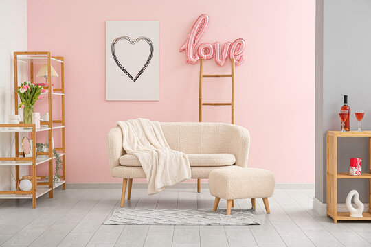 Interior of festive living room with white sofa, word LOVE made from balloons and decorations for Valentine's Day celebration