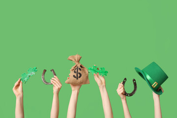 Female hands holding different party decor for St. Patrick's Day celebration on green background