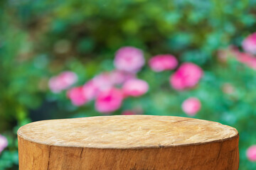 Empty old tree stump table top with blur rose garden background for product display