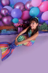 menina sorridente com roupa de sereia em cenário fundo do mar, ensaio de aniversário temático...