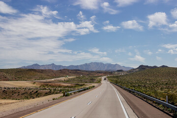 Scenic highway 40 near Phoenix in Arizona, USA. Beautiful road landscape on a sunny summer day. Nature in desert with mountain, blue sky and white clouds. 