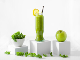 Healthy green juice made from kale and green apple with a slice of lemon in a tall glass on a white background; copy space