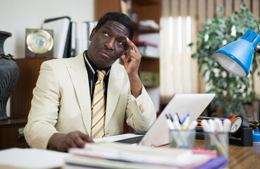 Focused african american businessman works in the office at an computer while sitting at workdesk