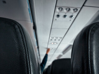 photo of rows of airplane seats and someone's hand adjusting the lights inside the plane