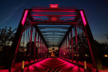 Pink-Lit Truss Bridge at Blue Hour, Wooden Deck Perspective