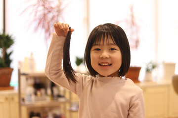 美容室で髪を切る女の子　ヘアドネーションイメージ - obrazy, fototapety, plakaty