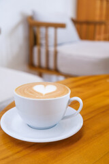 Heart latte art in a white cup placed on a wooden table, inviting atmosphere