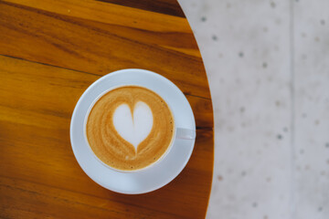 Top view of a cappuccino with heart-shaped latte art on a polished wooden table