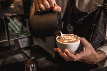 Fototapeta na wymiar Barista pouring white cream creative latte art coffee in coffee shop