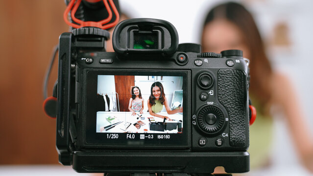 Rear view behide camera screen display two women influencer shoot live streaming vlog video review makeup social media or blog. Girl with cosmetic vivancy studio lighting for marketing recording.