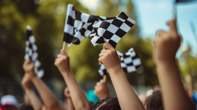 The camera zooms in on a of childrens hands each holding onto a small checkered flag and waving it with all their might.