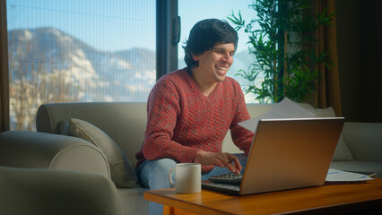 Overjoyed young man sit on couch in living room with laptop pay bills, use calculator count expenses, make budget control, manage finances