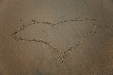 Drawn heart on wet sea sand. Love and tenderness at the resort. Close-up.
