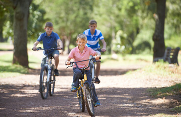 Nature, happy and portrait of children on bicycle riding in outdoor field, park or forest for exercise. Fun, cycling and confident young boy kids on a bike for cardio, hobby or training in a garden.