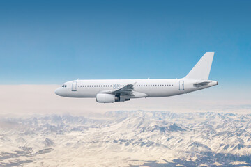 Fototapeta na wymiar White modern jet plane flies over snow covered mountains