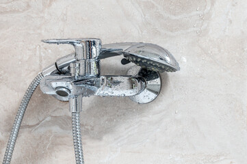 Faucet with shower in water drops in the bathroom.