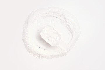 Washing powder in a measuring spoon on white background top view close-up.