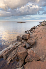 A calm evening on the rocks by the sea, moody sky and reflections on the water. Bothnian Bay, Baltic Sea, Finland