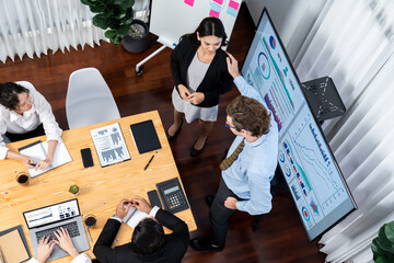 Wide top view of diverse group of business analyst team analyzing financial data report paper on meeting table. Chart and graph dashboard by business intelligence analysis. Meticulous