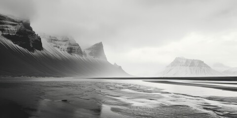 A monochrome image of a serene beach with majestic mountains in the backdrop. Suitable for various uses