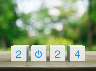 2024 start up business icon on white block cubes on wooden table over blur green tree in park,...
