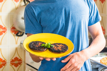 Young caucasian teenager Burned cooked hamburger with chef mistake at home - concept of cook in the kitchen for quarantine leisure indoor activity during lockdown
