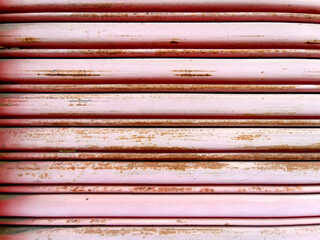 Rusty red metal background, old metal door, metal shutters with peeling paint. Front view of shutters with rust and deterioration from the elements. Ideal use as background wallpaper.