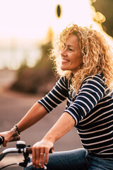 Cheerful beauiful blonde curly caucasian woman smile and enjoy the ride on a bike in outdoor...
