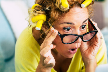 Funny and nice pretty woman surprised looking a laptop computer - yellow colors and curles foe home made getting ready hair style and concept of online shopping sales like black friday or cyber monday