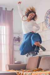 Joyful lifestyle and success concept for female people - woman jumping on the couch for happiness -...