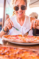 Happy young adult caucasian woman ready to eat a beautiful and tasty healthy pizza at the restaurant - concept of happy people and food relationship - italian style life and summer leisure vacation