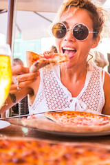Happy young adult caucasian woman eating a beautiful and tasty healthy pizza at the restaurant -...