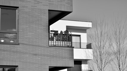 Fragment of the building's facade with windows and balconies. Modern apartment buildings on a sunny day. Facade of a modern residential building. Black and white.