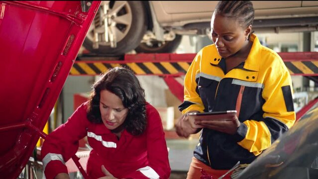 American and African women mechanic Checking and a list of items that need to be repaired related to the engine in the garage, couple girl worker work together in the garage 