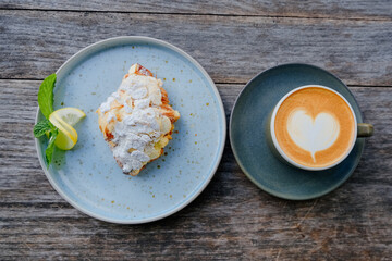 Almond croissant and heart latte art, outdoor setting