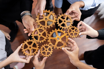 Group of multiracial business people joining gear wheels together as effective unity and productive teamwork concept. Efficient system business team process for solution solving. Meticulous