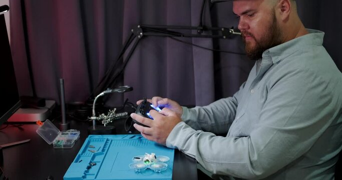 Test flight of the FPV drone after repair. A close-up of the hands of an engineer who repairs drones and checks his work. A young man is engaged in his hobby at home in the evening.