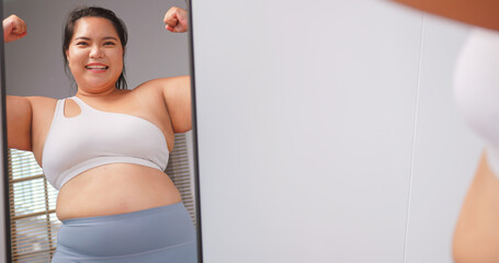 A chubby Asian woman feels confident and proud of her body while standing in front of the mirror.