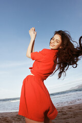 Fototapeta na wymiar Joyful Woman Dancing on the Sandy Beach under the Blue Sky