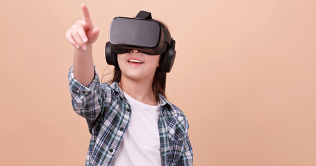 A girl having fun with game while wearing virtual reality glasses. Isolated on brown background in studio.