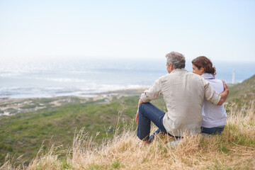 Fototapeta premium Old couple, hug and sitting on a mountain with love in marriage, retirement or holiday mockup space. Summer, vacation and man and woman embrace with support, care or trust with view of sea or ocean