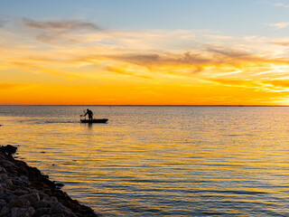 Fototapeta premium Fisherman in Small Boat at Sunset on The Laguna Madre, Bird Island Basin, Padre Island National Seashore, Corpus Christ, Texas, USA