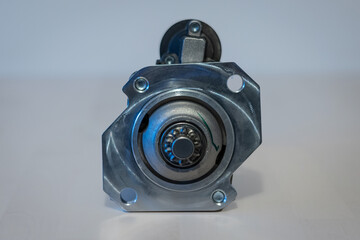 Rear view of automotive engine starter. Visible black refurbished and painted body, rear cog,...