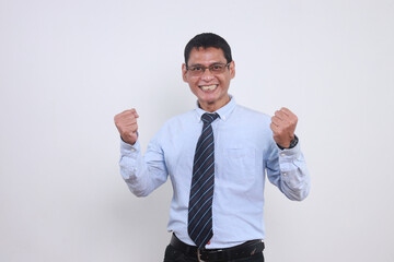 Excited Asian businessman raising both fist showing victory gesture with happy expression