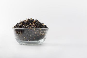 Black wolfberry or black goji berry in clear glass cup on isolated white background.
