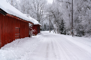 White snowy road with red farm building beside