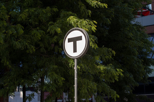 Cambridge, MA, USA - June 30, 2022: The "T" logo signpost made by the Massachusetts Bay Transportation Authority (MBTA) is seen at the Kendall Square outside MBTA's Kendall MIT Station in Cambridge.