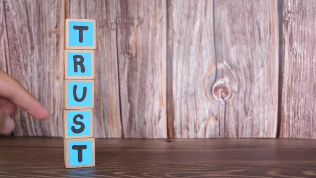 Broken trust concept. Human hand destroying wooden blocks with word trust 4K footage.